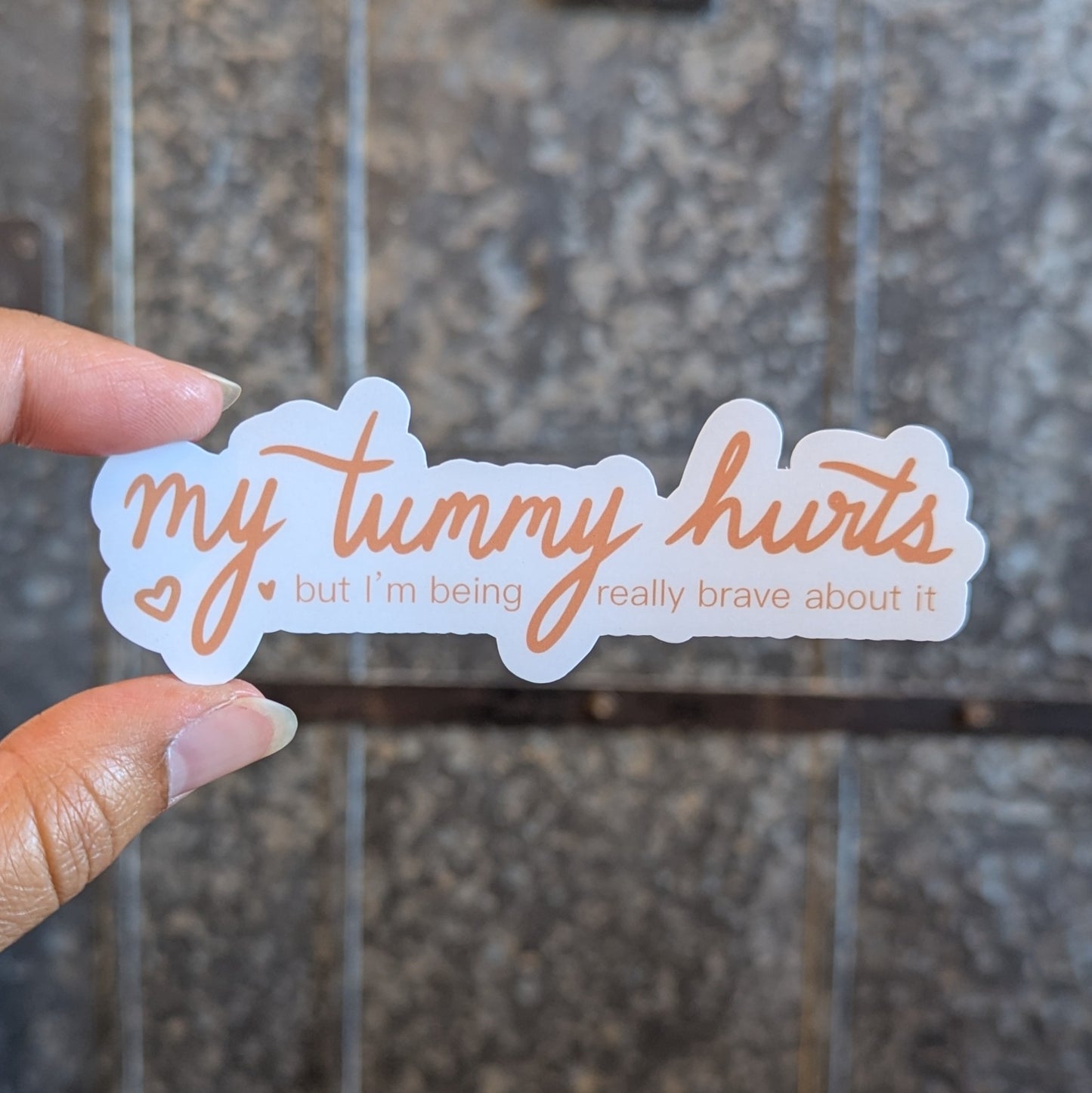 Sticker says "my tummy hurts" in script and "but I'm being really brave about it" in small print underneath