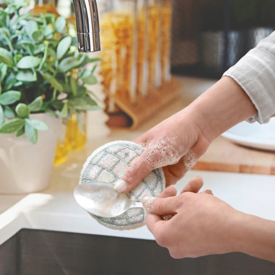Disco scrubbing sponge being used to clean a spoon