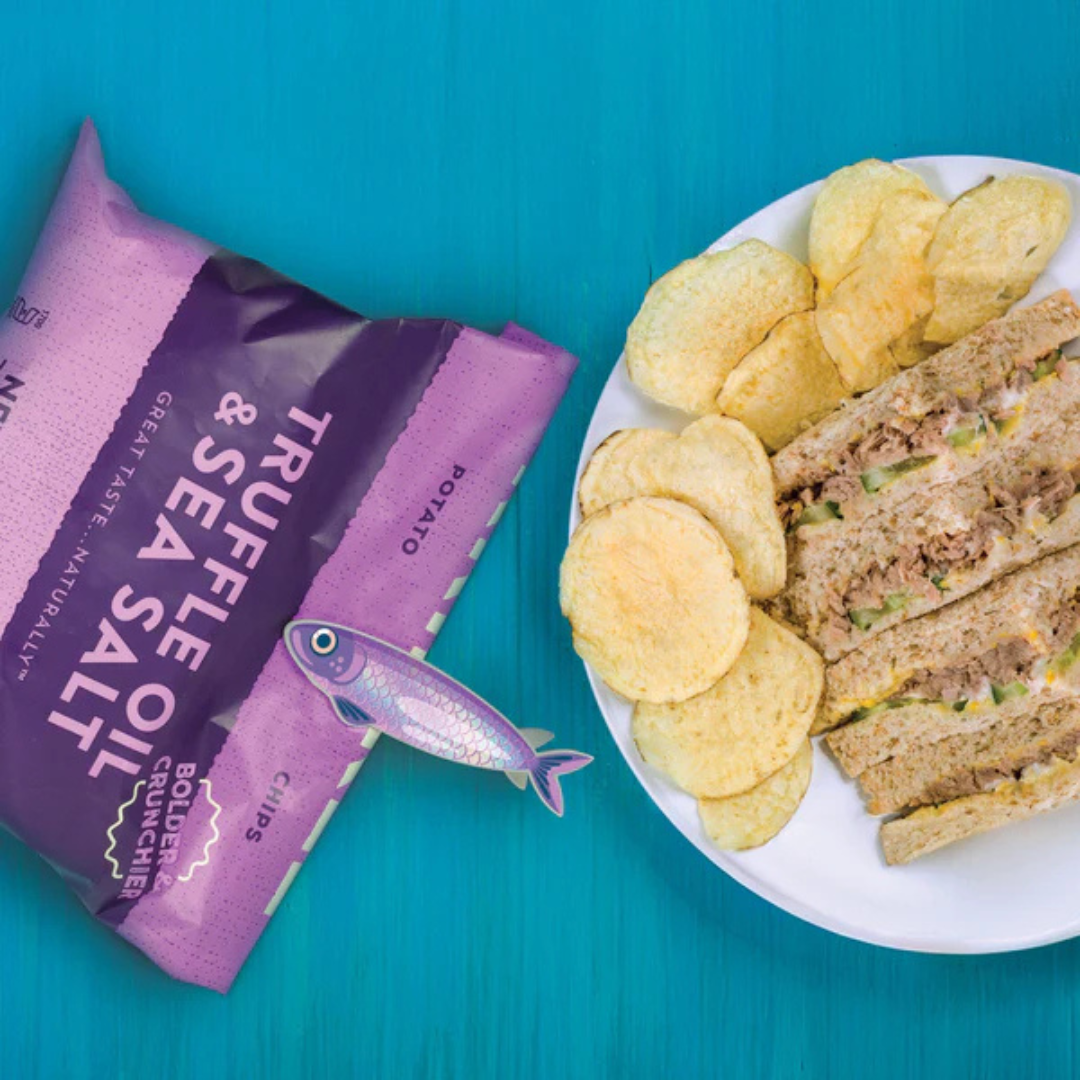 Purple fish clip on a purple bag of chips alongside a plate of chips and a tuna salad sandwich