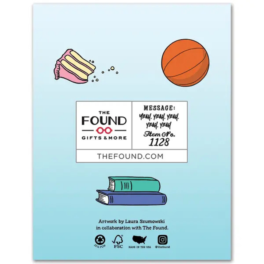 Back of card is blue with a slice of pink frosted cake, a basketball, and a stack of books