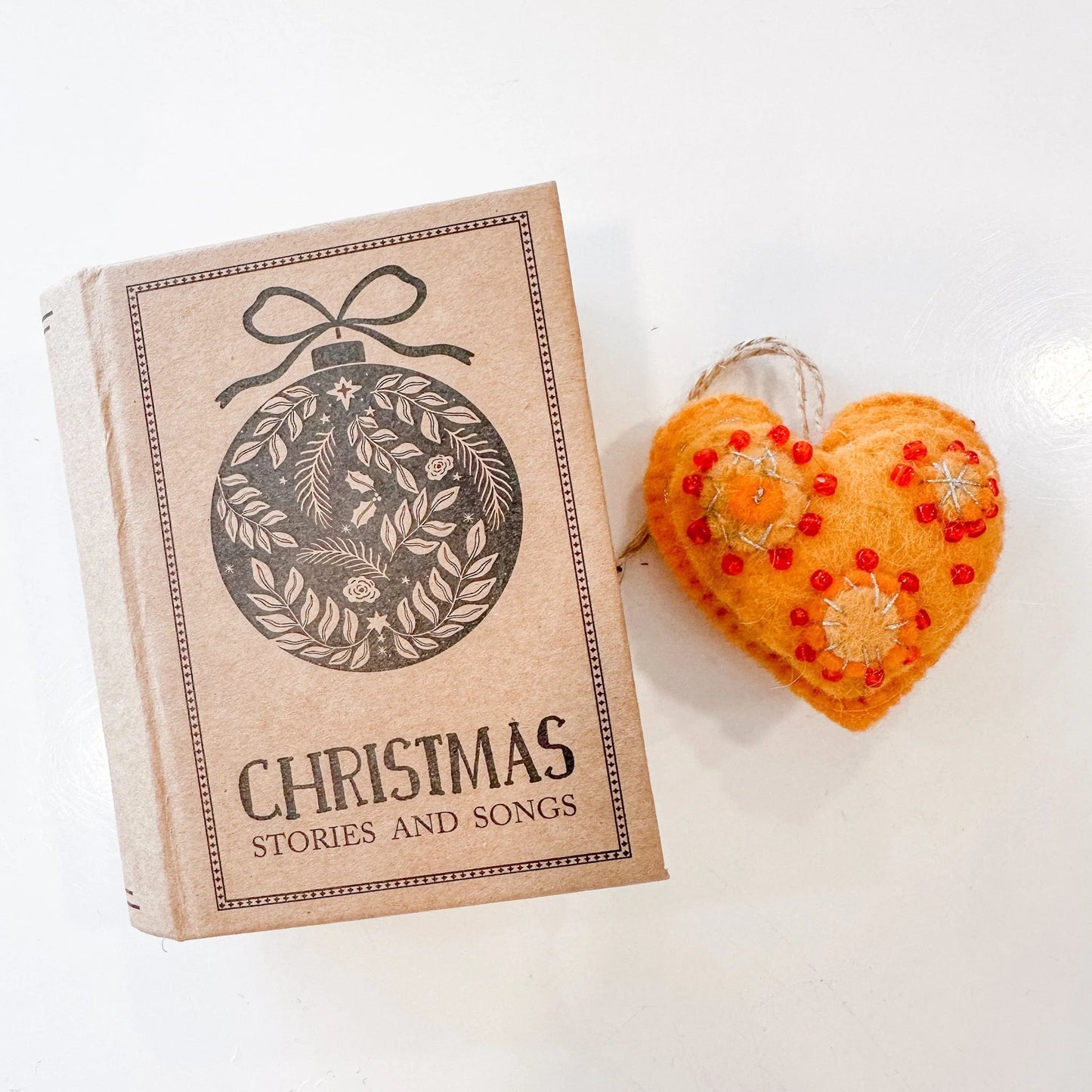 Gold yellow heart with red beads and gold embroidery with a book-shaped box that reads "Christmas stories and songs"