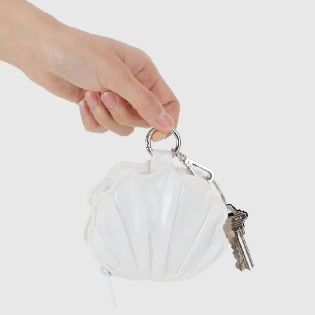 hand holding shell shaped coin purse with keys attached