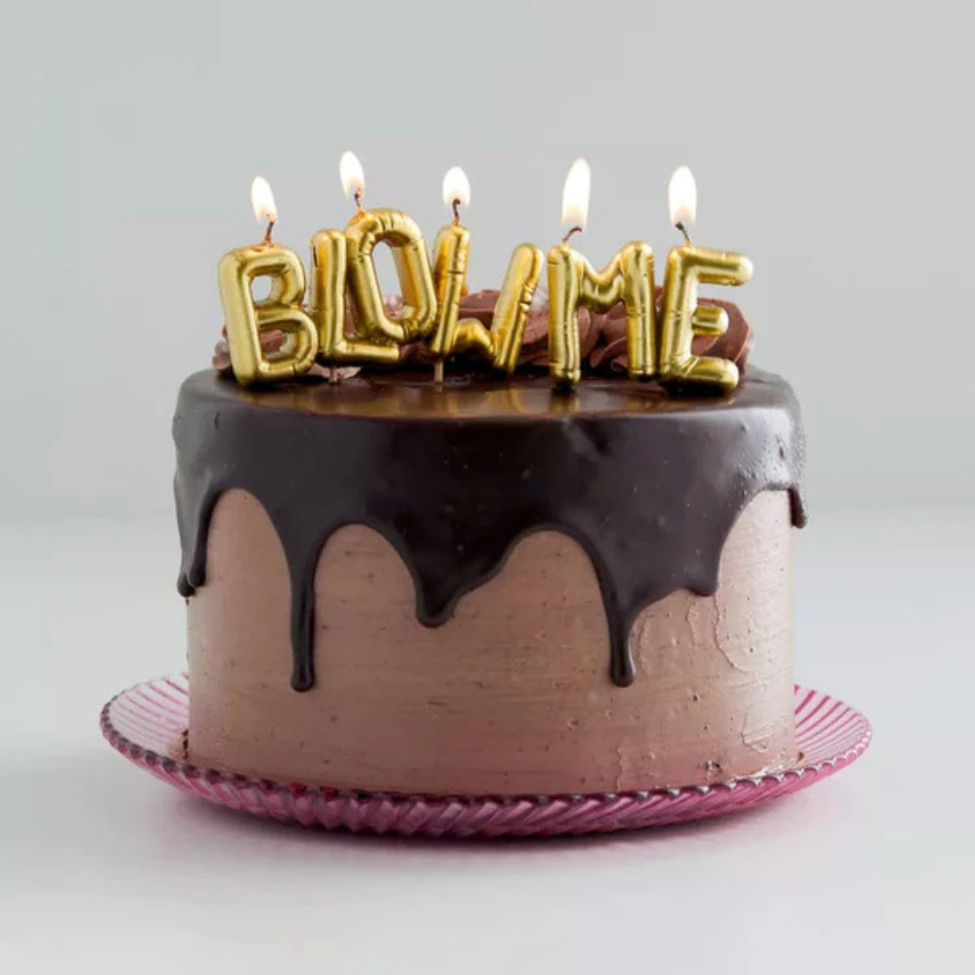 "BLOW ME" candles lit up on a very decadent looking chocolate cake