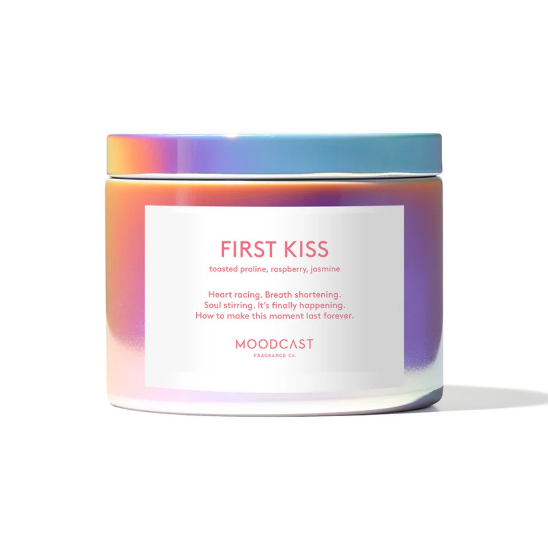 Iridescent candle with a label that reads "First Kiss - toasted praline, raspberry, jasmine
Heart racing. Breath shortening. Soul stirring. It’s finally happening. How to make this moment last forever.
Moodcast"
