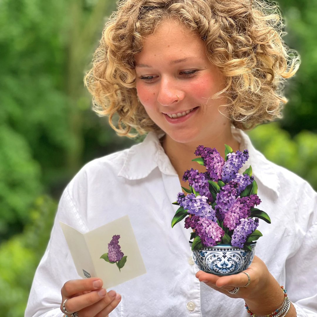 Woman holds the mini bouquet in one hand and the included card in the other.