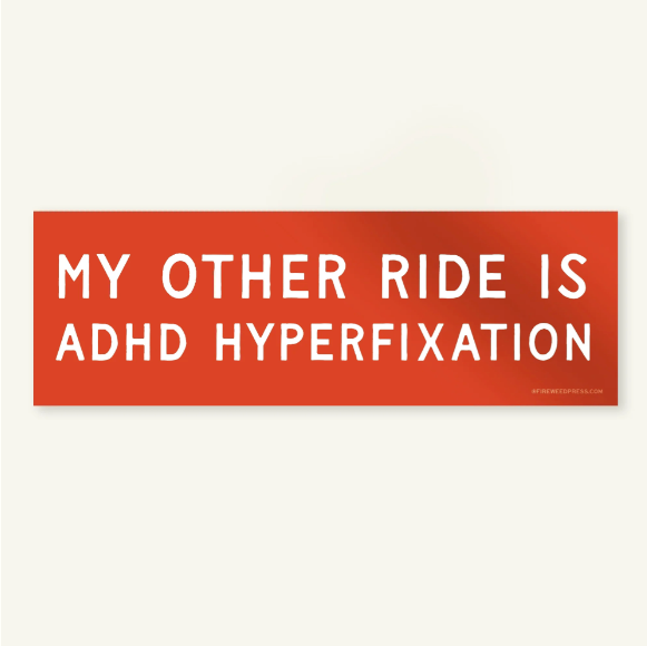 A rectangular bumper sticker with a red-orange gradient background and bold white text reading 'MY OTHER RIDE IS ADHD HYPERFIXATION'.