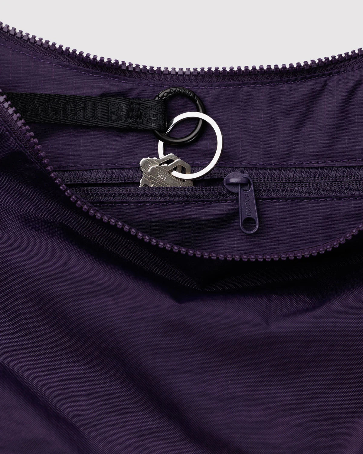 Close-up of a purple purse with a zipper and a brand logo on a white background