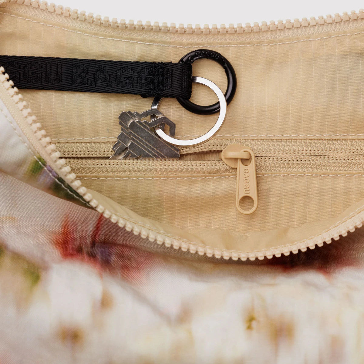 Close-up of a beige purse with a zipper, containing a key and black strap.