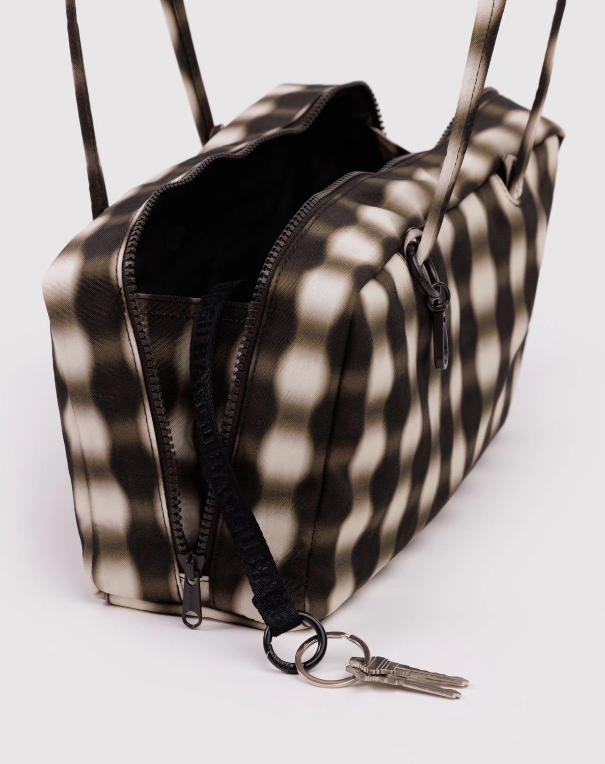Black and white checkered bag with a keychain on a light gray background