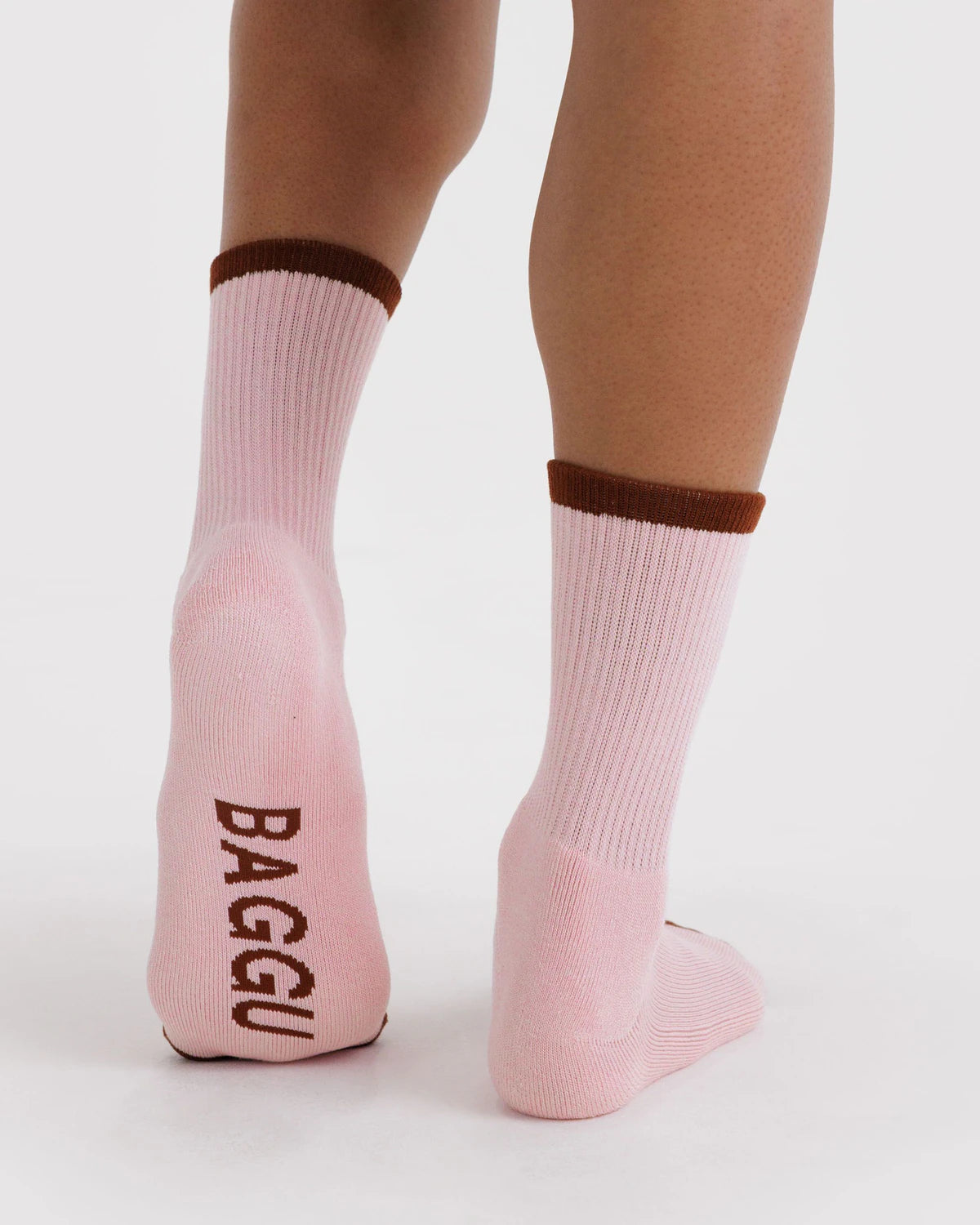 Pink socks with brown accents worn by a person on a white background