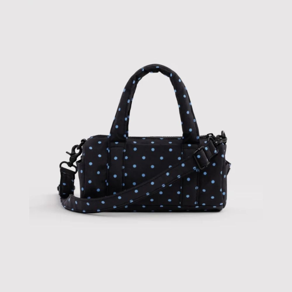 A black nylon handbag with a light blue polka dot pattern, featuring dual top handles, a detachable shoulder strap, and a zip-around closure, shown against a light gray background.