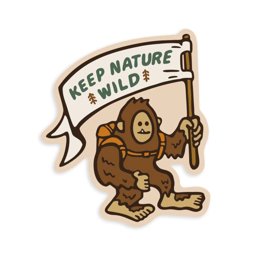 Little one toothed backpack wearing Sasquatch holds a flag that says "Keep Nature Wild"