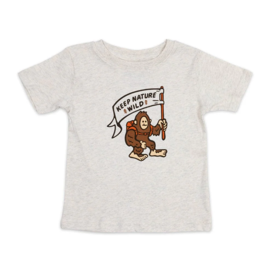 Cream color t-shirt with an adorable Sasquatch wearing a backpack and holding a flag that says "Keep Nature Wild"