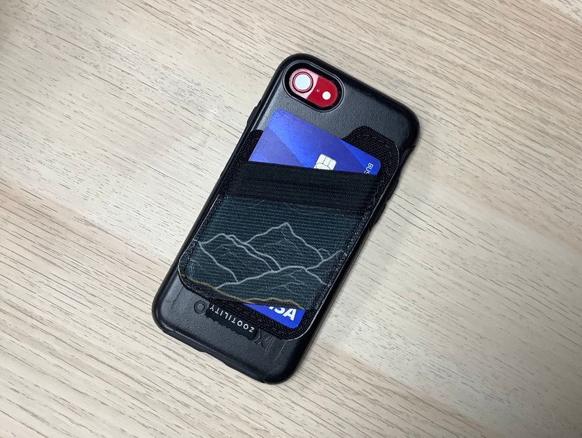 Magnetic phone elastic wallet in use on the back of a phone holding a credit card.