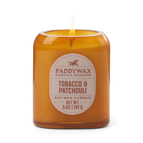 Candle in an amber glass vessel with a label that features the Paddywax horse logo.