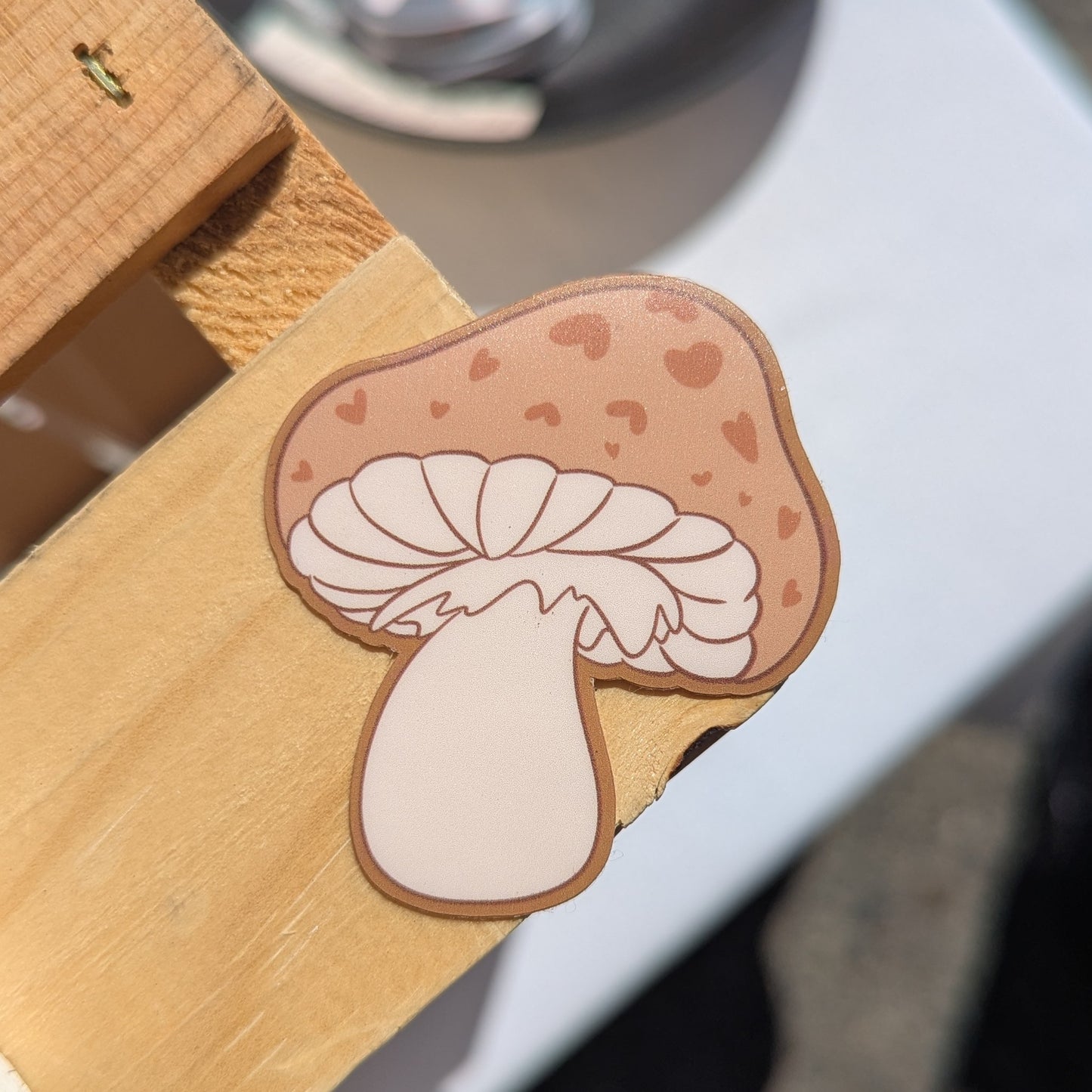 Brown and beige mushroom sticker has hearts on the mushroom cap