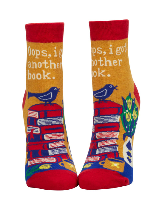 Colorful socks with book and bird design on a white background. Text reads "oops, I got another book"