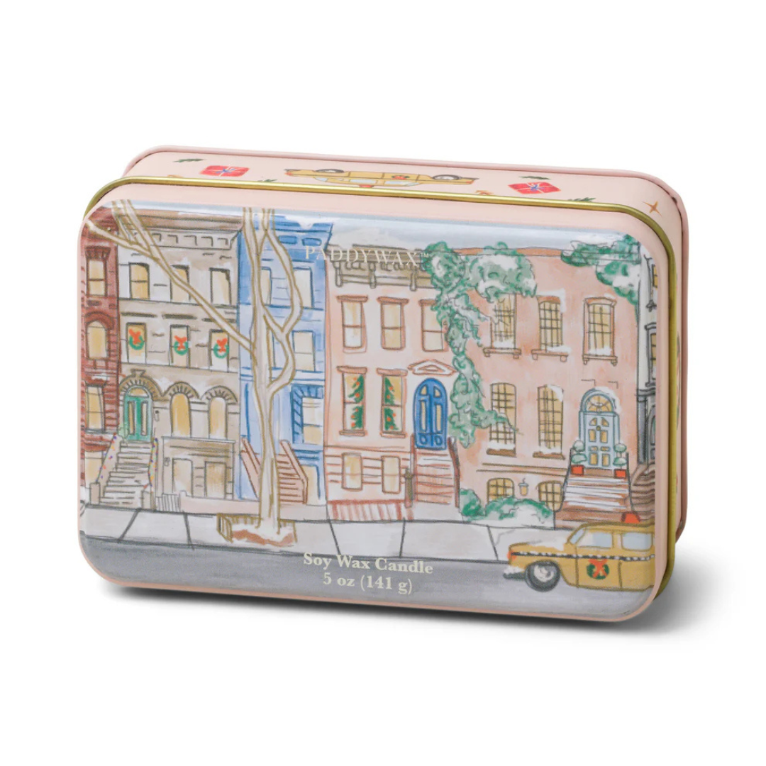 Pink holiday tin box featuring a city street decorated for the holidays with wreaths and red bows and snow capped trees.