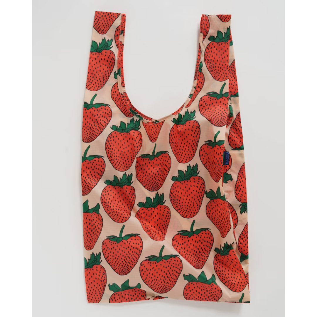 Peach colored oversized reusable tote bag featuring an all over print of bright red strawberries.