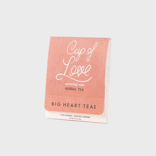 White tea bag with a peach colored logo with the title "Cup of Love" in white cursive above the words "nurturing rose herbal tea" and the brand name "Big Heart Tea Co" in black lettering.