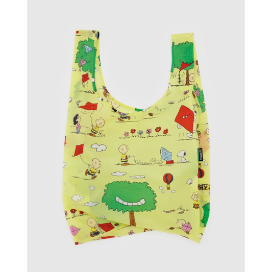 Yellowish green reusable tote bag featuring a Charlie Brown and Snoopy print flying kites into trees. 