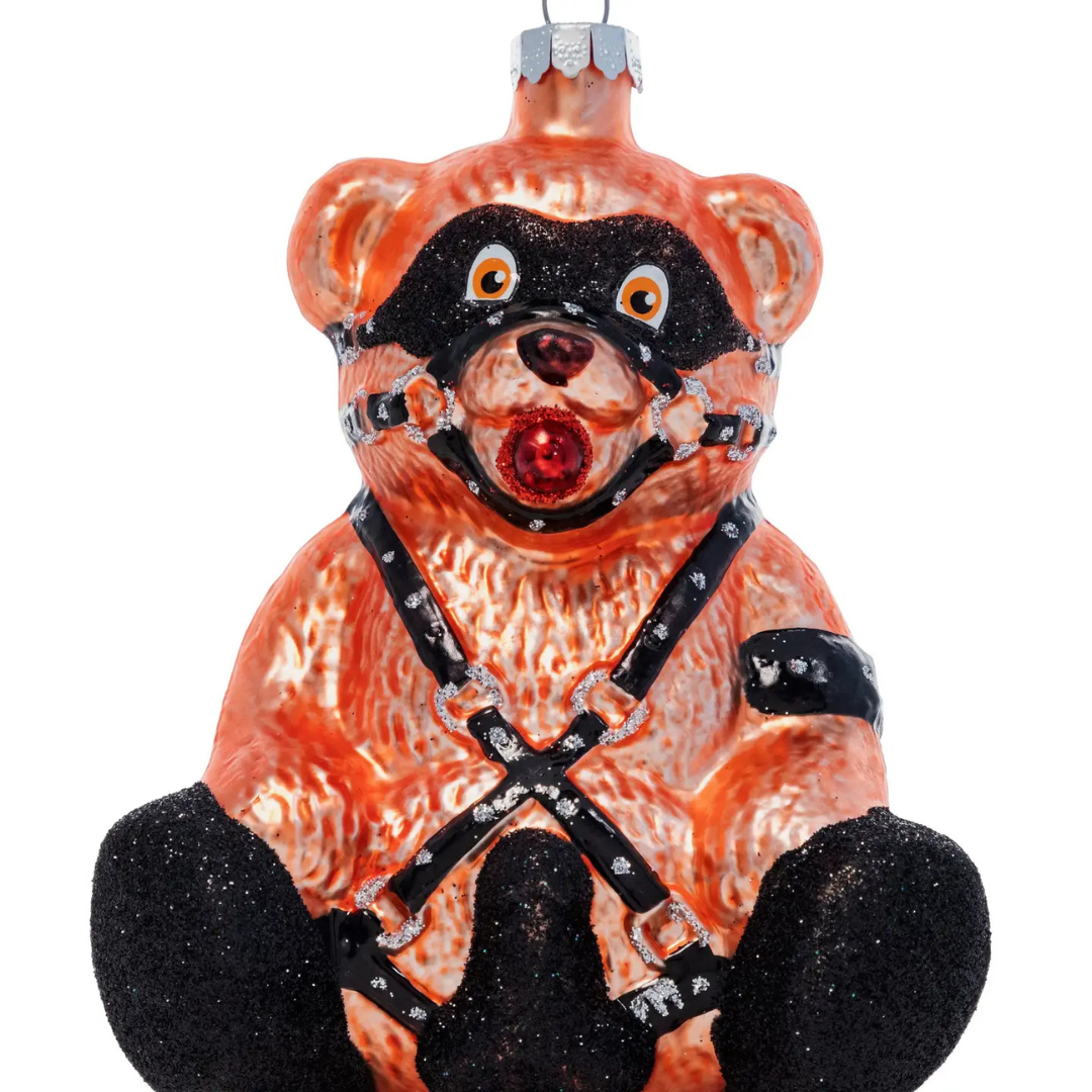 Brown teddy bear shaped ornament wearing black straps and chains.