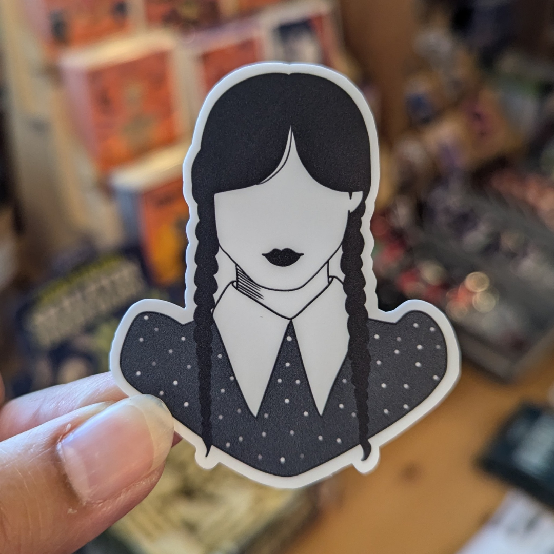 Sticker features bust of Wednesday Addams with two dark braids, dark lips and collared shirt