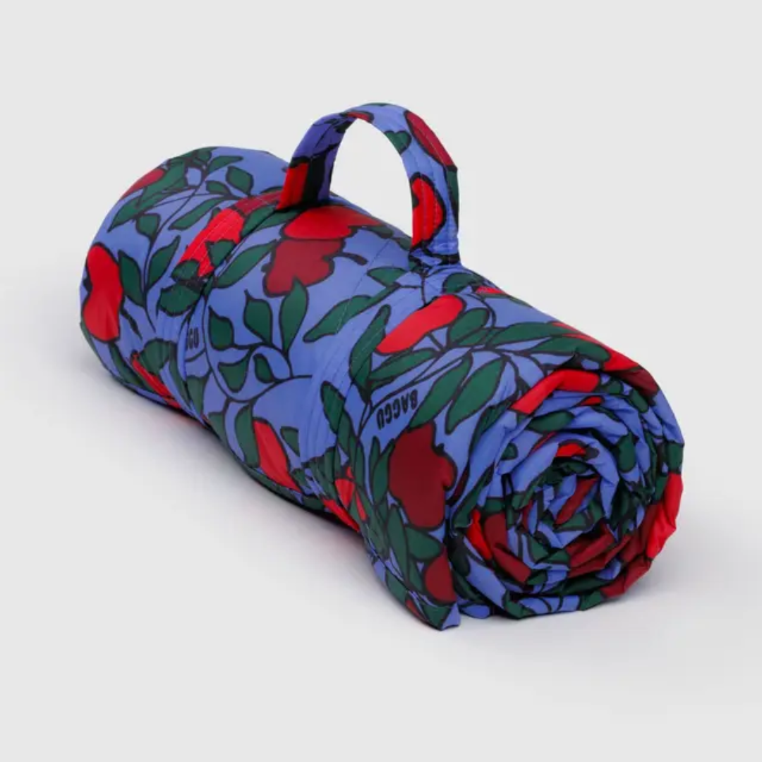 Rolled-up picnic blanket with red apple and green leaf pattern 