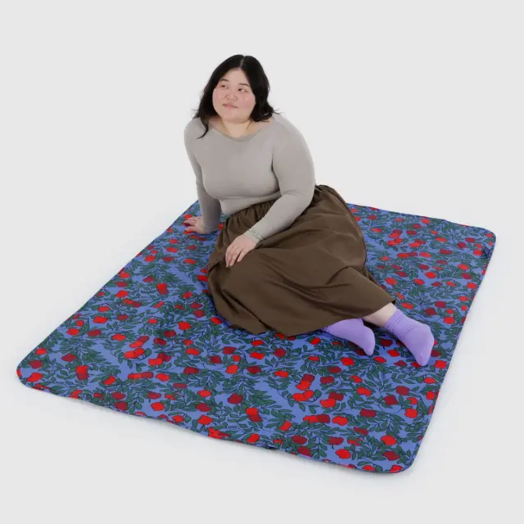 Model sitting on apple patterned blanket 
