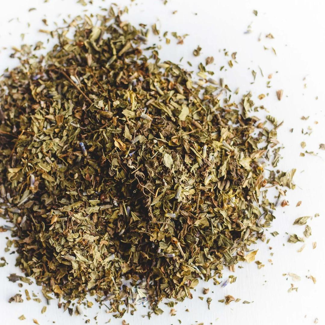 Loose tea leaves consisting of spearmint, peppermint and lavender against a white background.