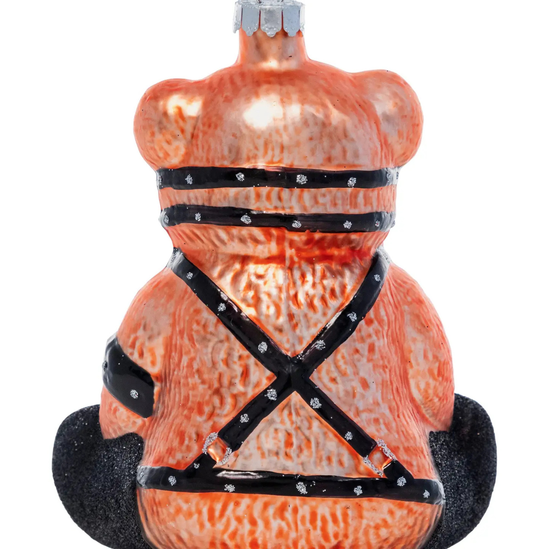 Back of brown teddy bear shaped ornament wearing black straps and chains.