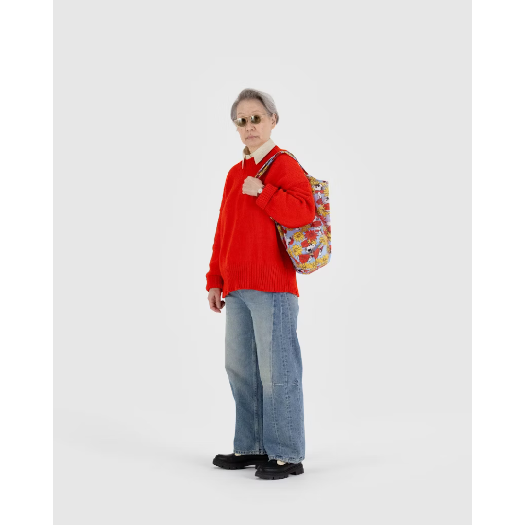 Woman carrying periwinkle reusable tote bag featuring a red and yellow floral pattern with Snoopy in a red coat.