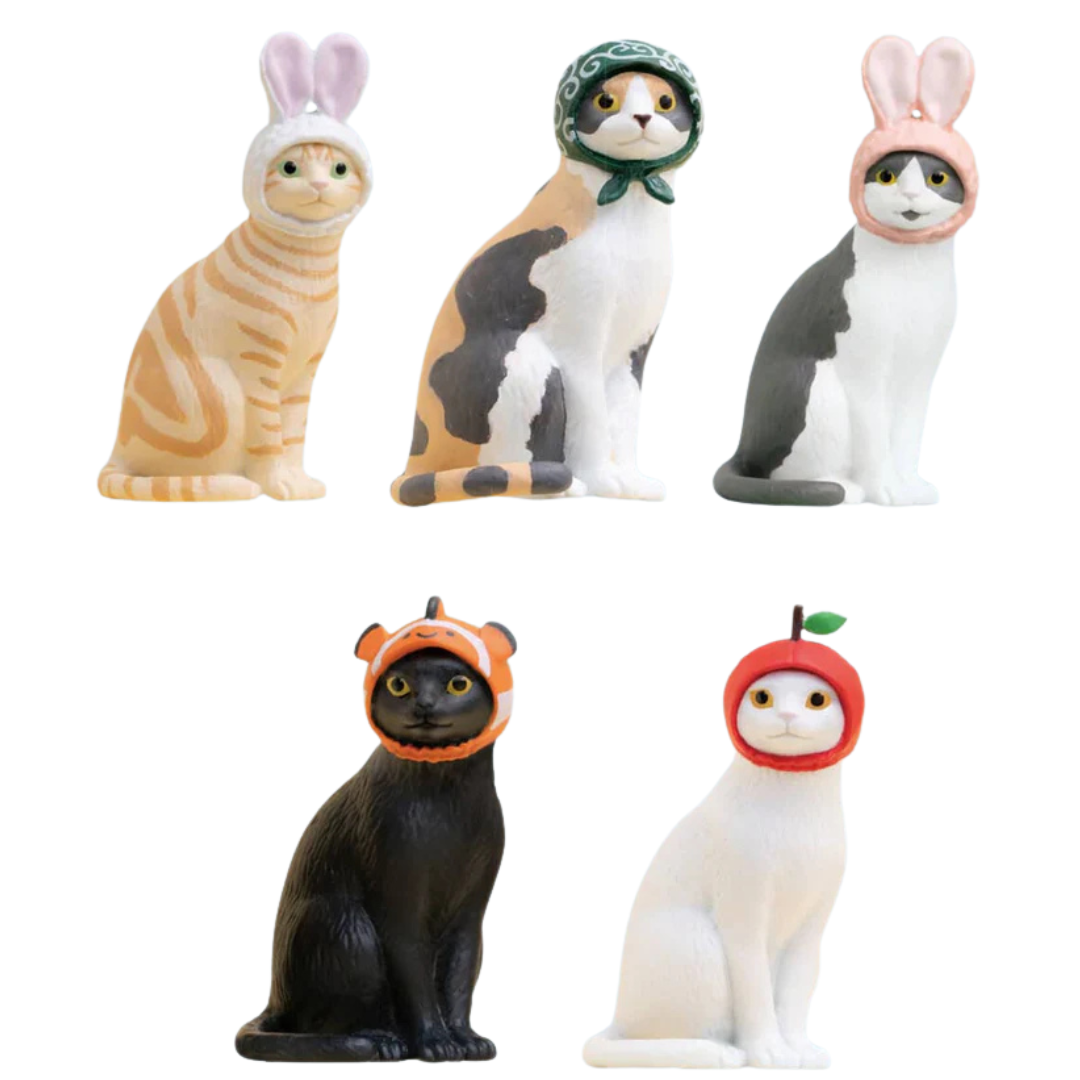 The possible options you'll find in the cat cap blind box: an orange cat in bunny ears, a calico in a head scarf, a gray tuxedo in bunny ears, a black cat in a clown fish, and a white cat in an apple.