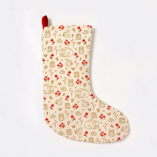 Creamy off-white stocking with a red hook to hang, featuring woodland forest creatures in a gold pattern with red mushrooms to match.