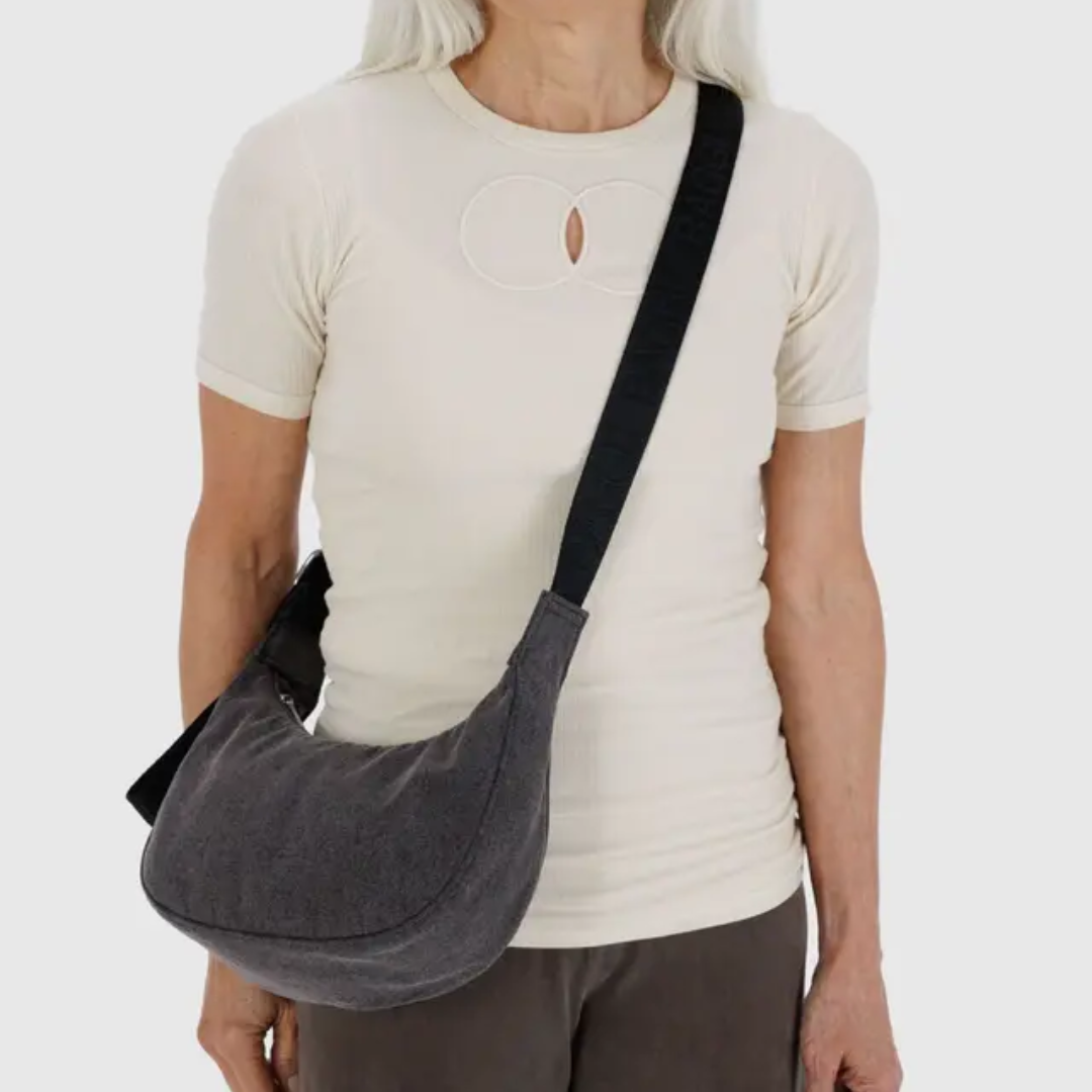 model wearing the crescent shaped shoulder bag with a black strap. Bag falls just below their waist