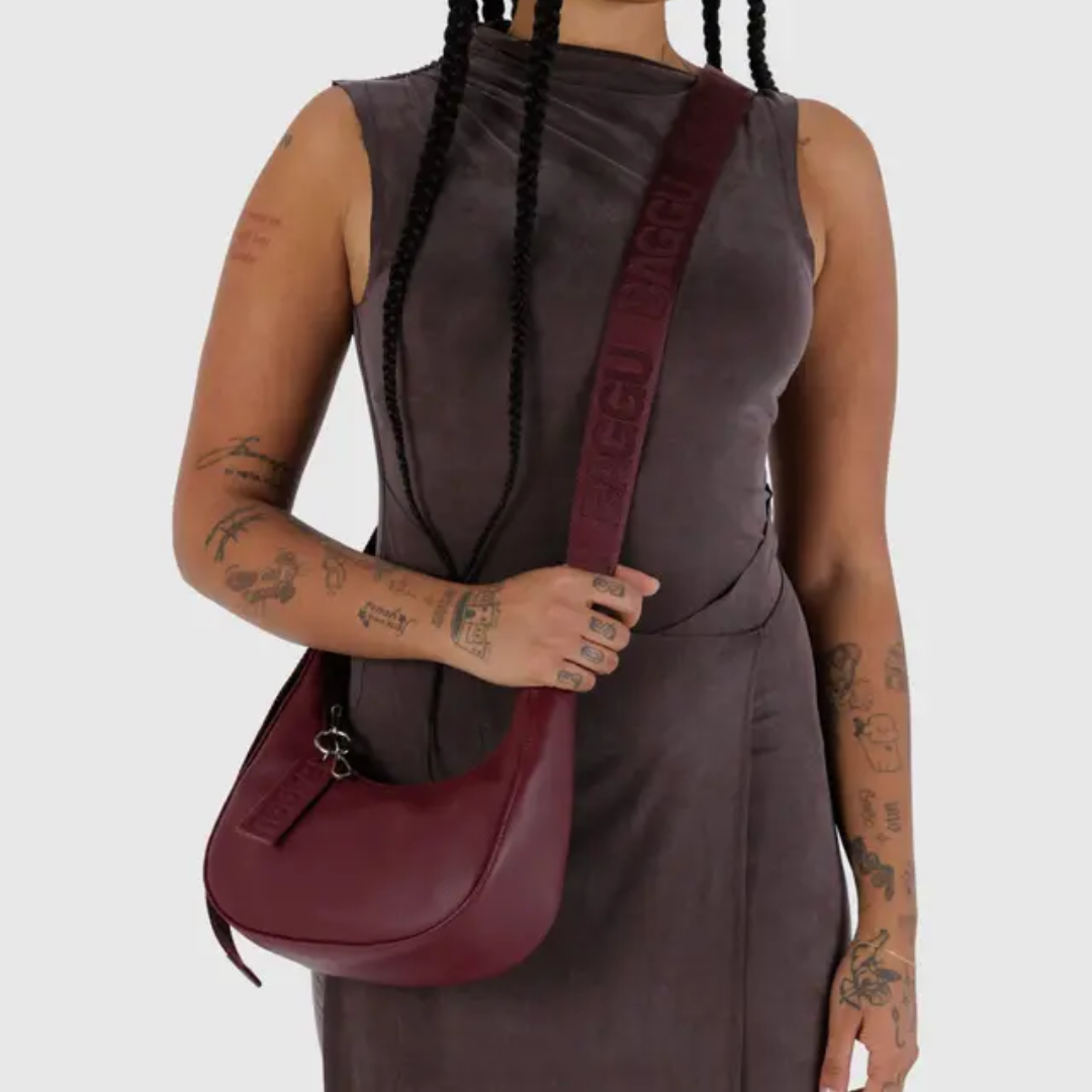 Model wearing the small crescent bag with he strap adjusted so that it hits at their hip.