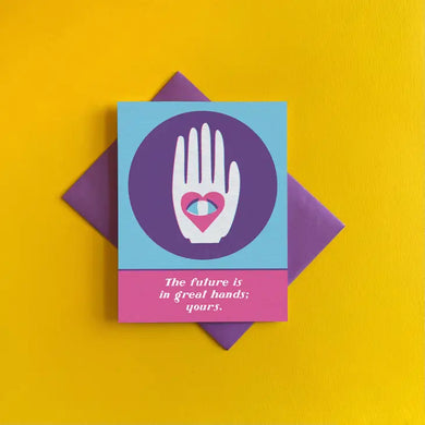 Yellow background, purple card envelope, greeting card with pink and blue color block background and white hand with heart and eye in middle. White text reads 