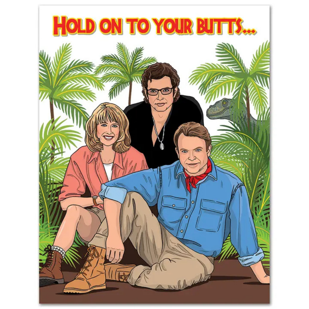 Jeff Goldblum, Laura Dern, and Sam Neil as their Jurassic Park characters pose in front of jungle greenery as a T-rex looks stalks them. The card reads "Hold on to your butts..." in the Jurassic Park font.