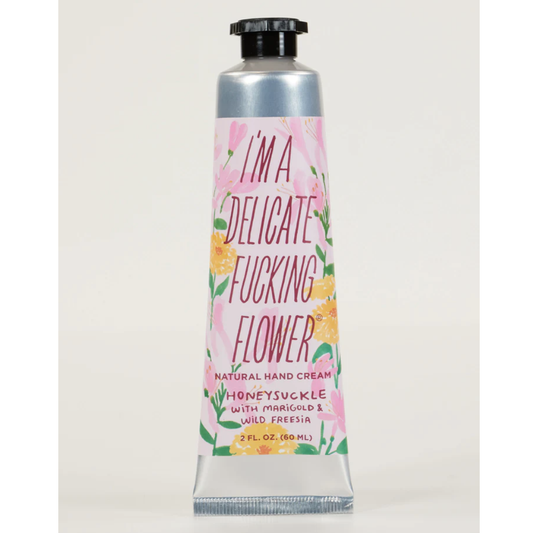 Hand cream tube with floral design in pink and yellow that says "I'm a delicate fucking flower - natural hand cream - honeysuckle with marigold & wild freesia 2 fl oz"
