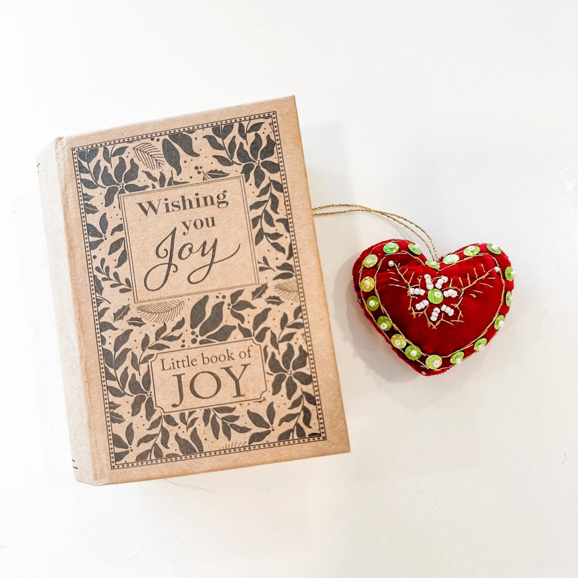 Red Velvet heart decorated with gold embroidery and green and white beads and sequins with a book-shaped box that says "Wishing you joy/Little book of Joy"