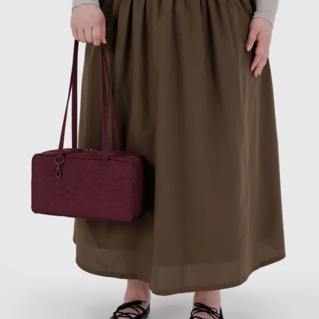 Model holding the bag by the strap for scale.
