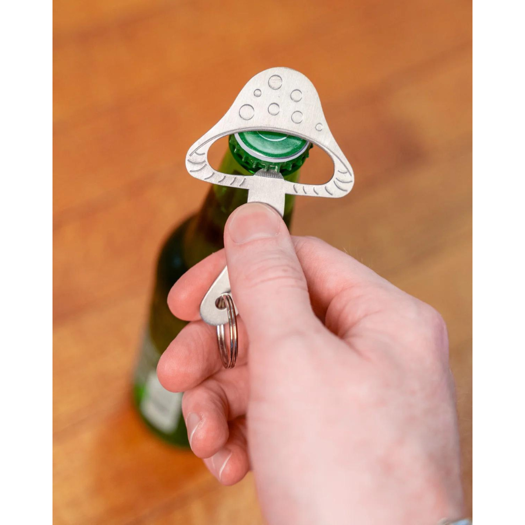 Person using silver mushroom shaped bottle opener to open glass bottle.