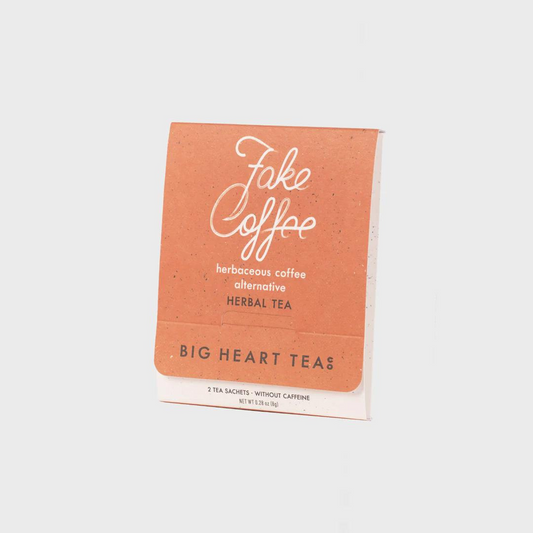 White tea bag with an orange label featuring the flavor "Fake Coffee" in white cursive above the words "herbaceous coffee alternative, herbal tea" and the brand name "Big Heart Tea Co" in black lettering.