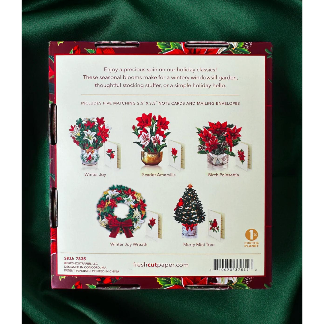 Back of holiday greeting card box trimmed with poinsettias, lying on top of emerald green satin.