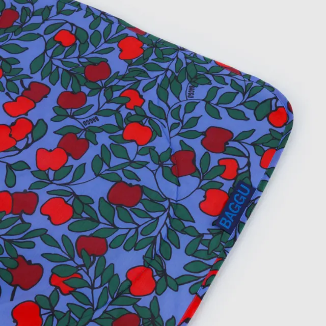 Detail of blanket is blue with red apple pattern and 'BAGGU' branding