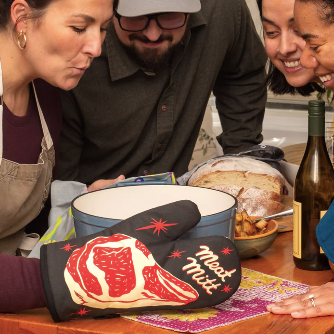 People gathered around a pot with one person wearing the "Meat Mitt"
