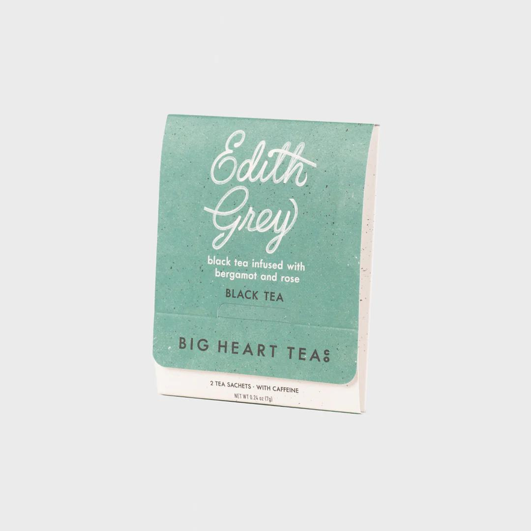 Turquoise label over white tea bag featuring the flavor "Edith Grey" in white cursive above the words "black tea infused with bergamot and rose black tea" and the brand name "Big Heart Tea Co" in black lettering.