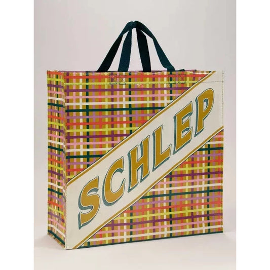 Tote bag with plaid background and large text that reads "Schlep"