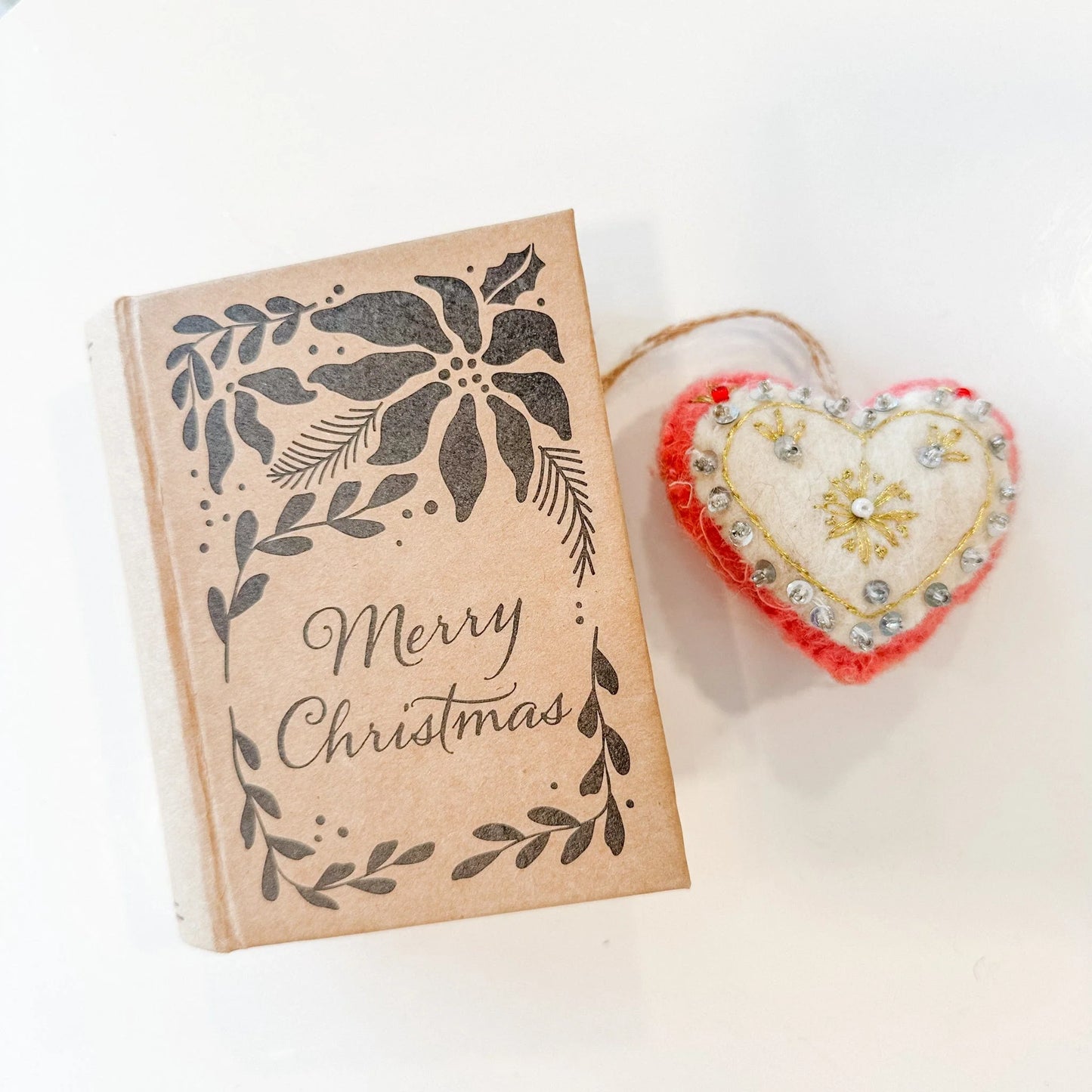 Red and white heart decorated with gold embroidery and silver beads and sequins with a book-shaped box that reads "Merry Christmas"