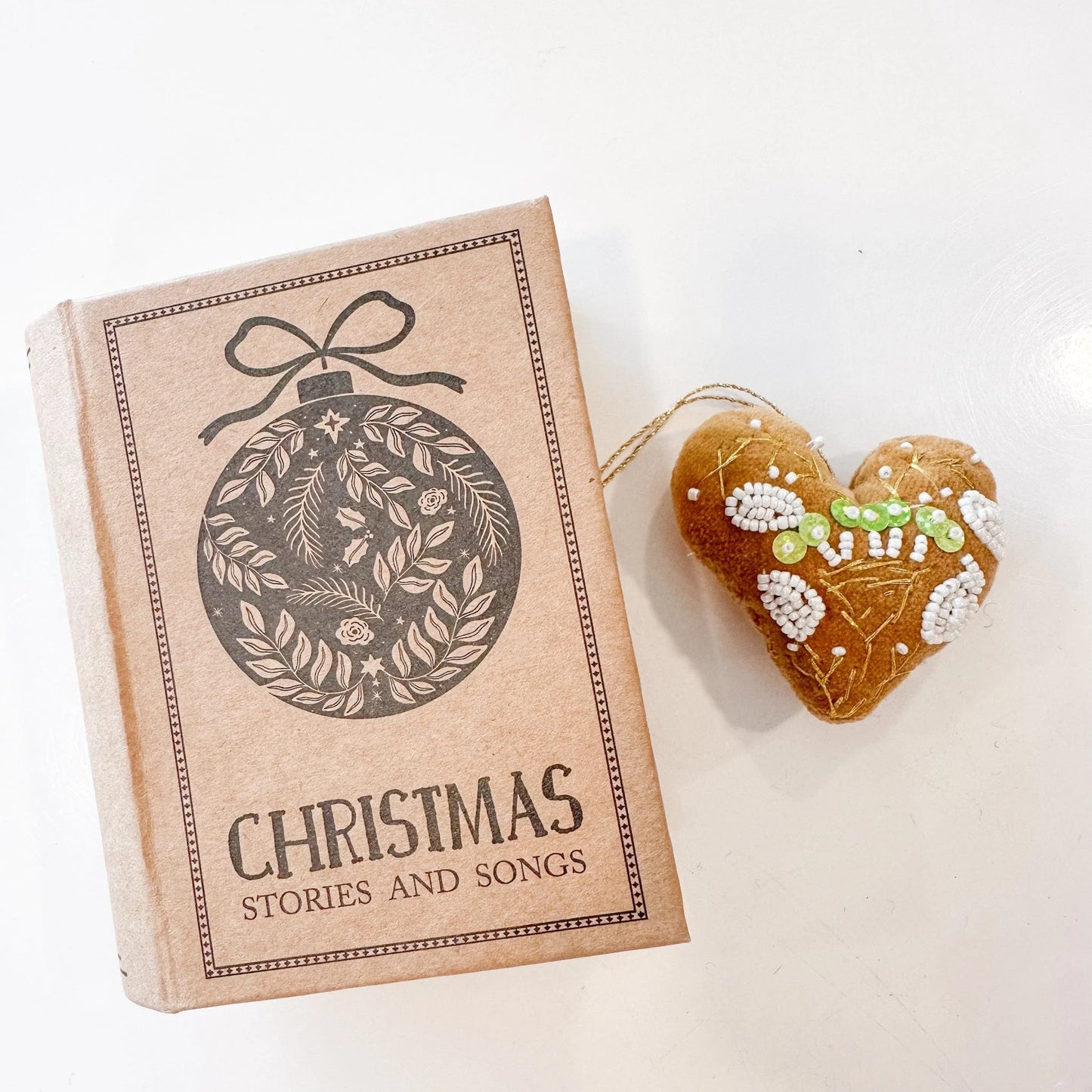 Mustard yellow velvet heart with white beads, green sequins, and gold embroidery with a book-shaped box that reads "Christmas stories and songs"